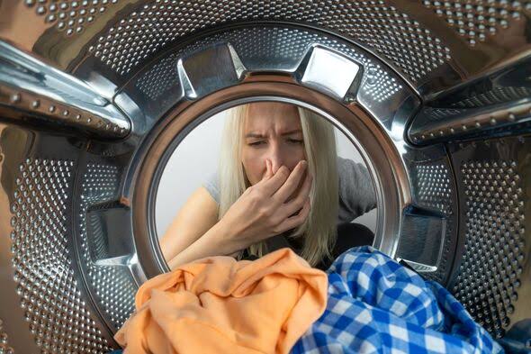 Woman reacting to smell from washing machine