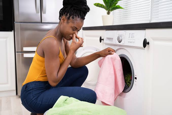 Woman pinching nose at smelly laundry